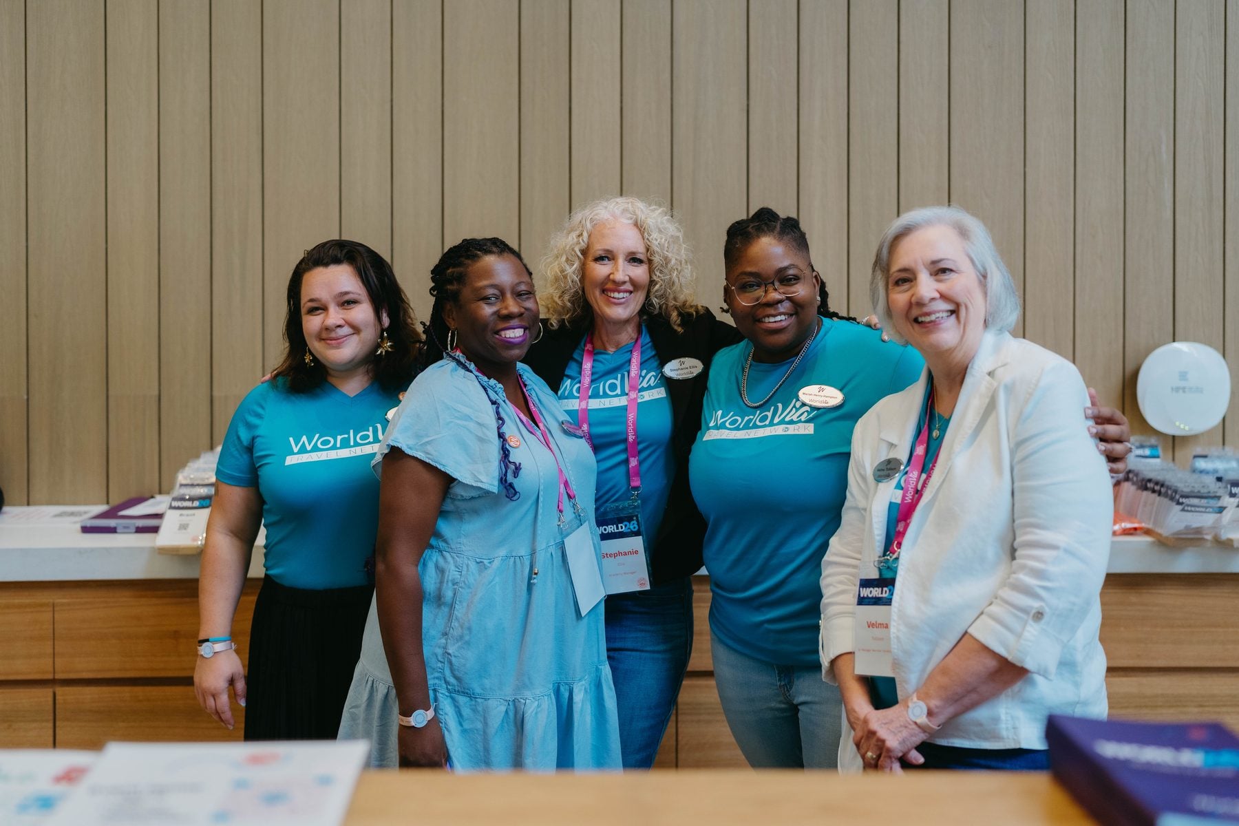 Team WorldVia smiling together at the WORLD26 check-in desk